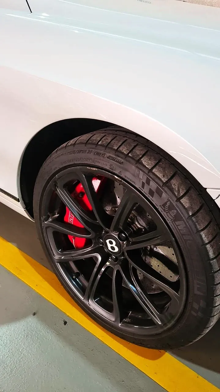 Bentley branco com roda pintada de preto e pinça de freio vermelha
