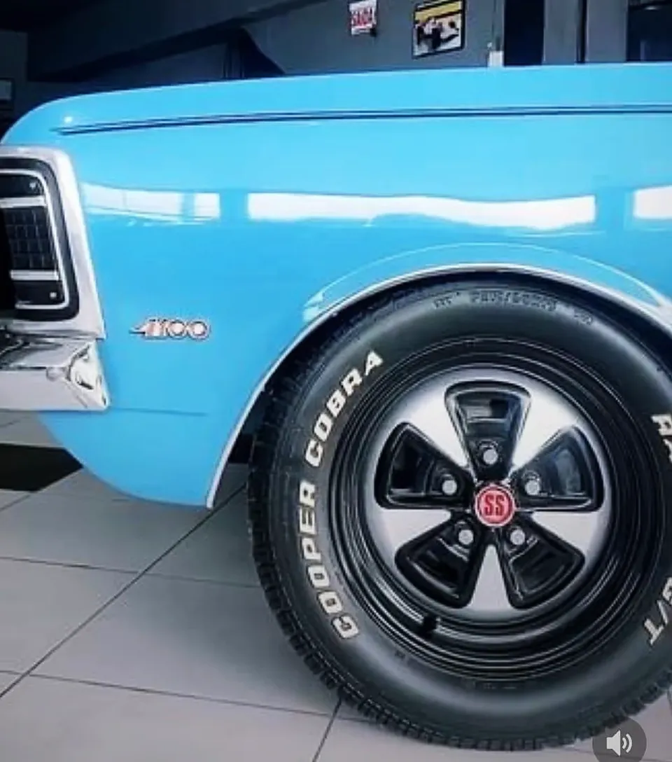 Carro clássico azul com roda pintada de preto e pneu de faixa branca