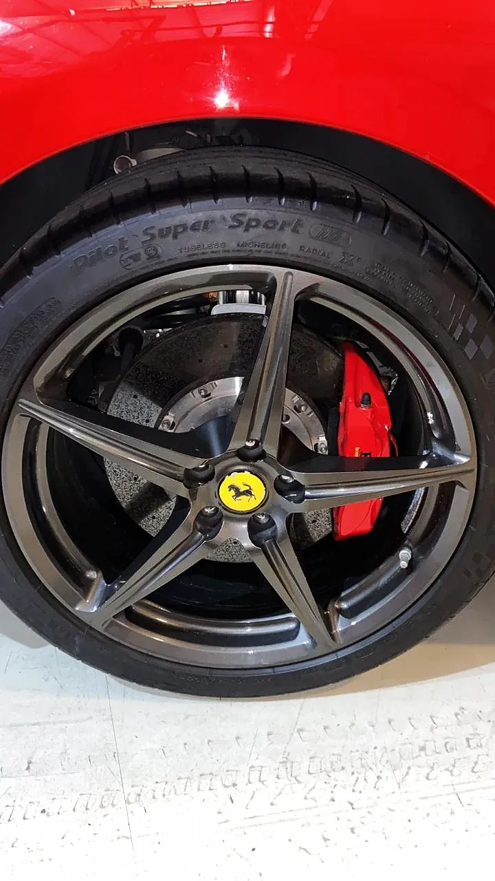 Ferrari vermelha com roda pintada de grafite e pinça de freio vermelha
