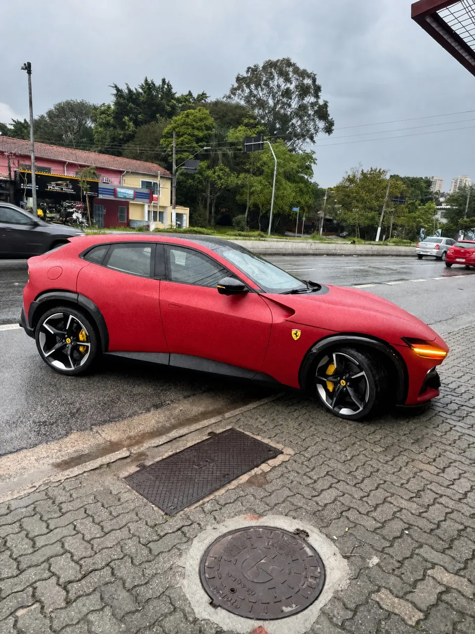 Ferrari Purosangue vermelha fosca vista de lado, em frente à RM