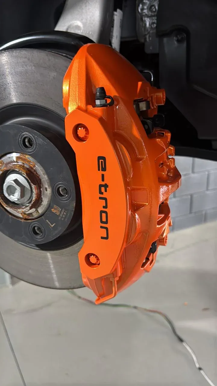 Pinça de freio Audi e-tron laranja com letras pretas, sobre o disco de freio