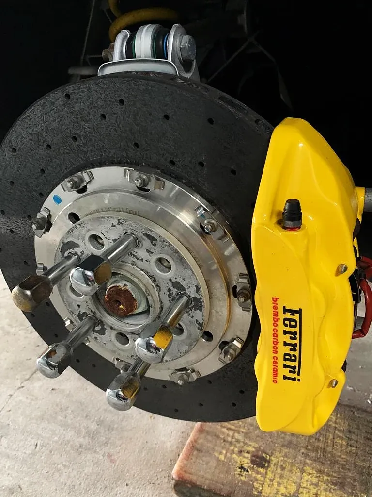 Pinça Ferrari pintada de amarelo, montada no cubo com disco carbono-cerâmico