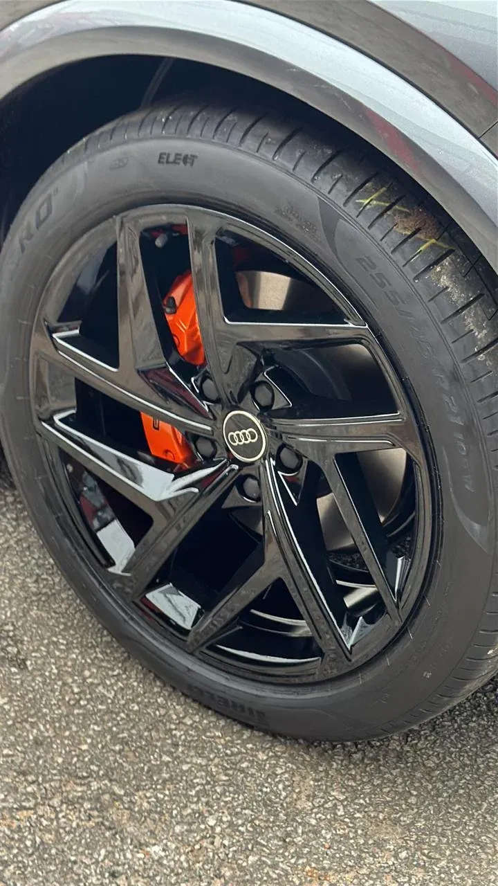 Roda Audi preta com a pinça de freio laranja aparecendo entre os raios