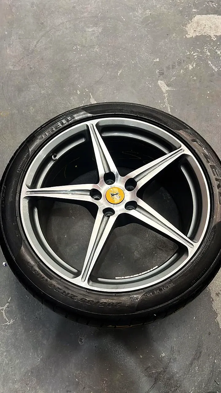 Roda Ferrari de cinco raios com face usinada, com pneu, sobre o piso