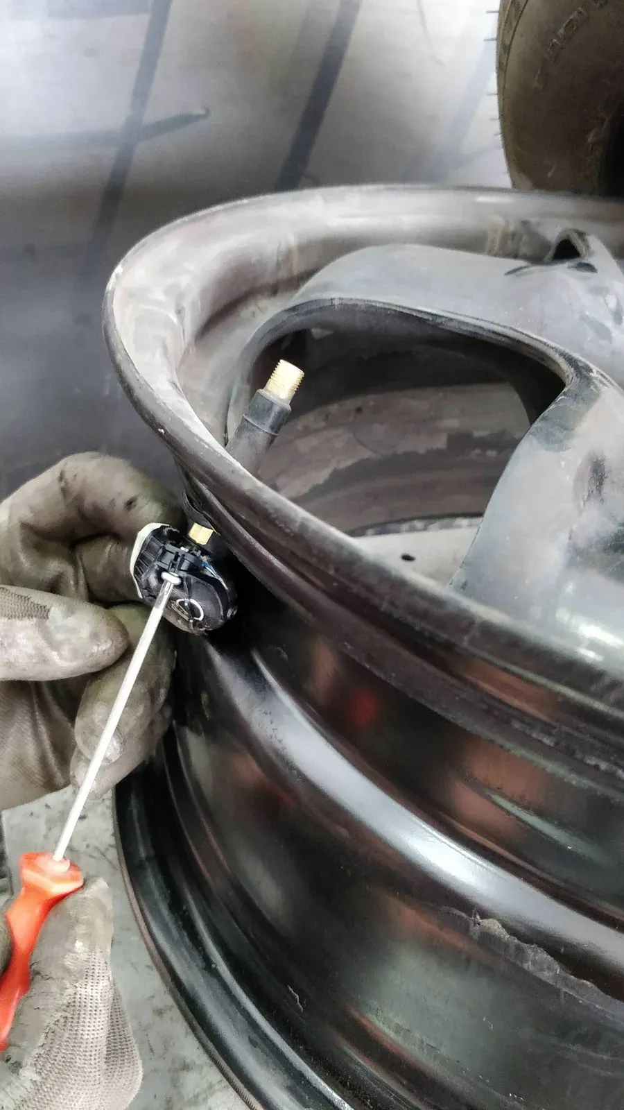 Sensor TPMS danificado sendo retirado de uma roda de aço